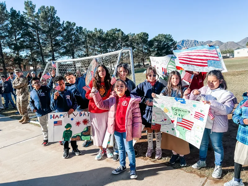 NECA students holding hand-made project posters outdoors on campus.