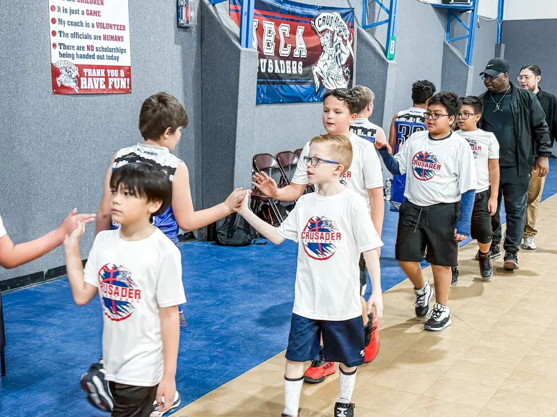 Young NECA students in Crusaders shirts encouraging each other in the school gym.