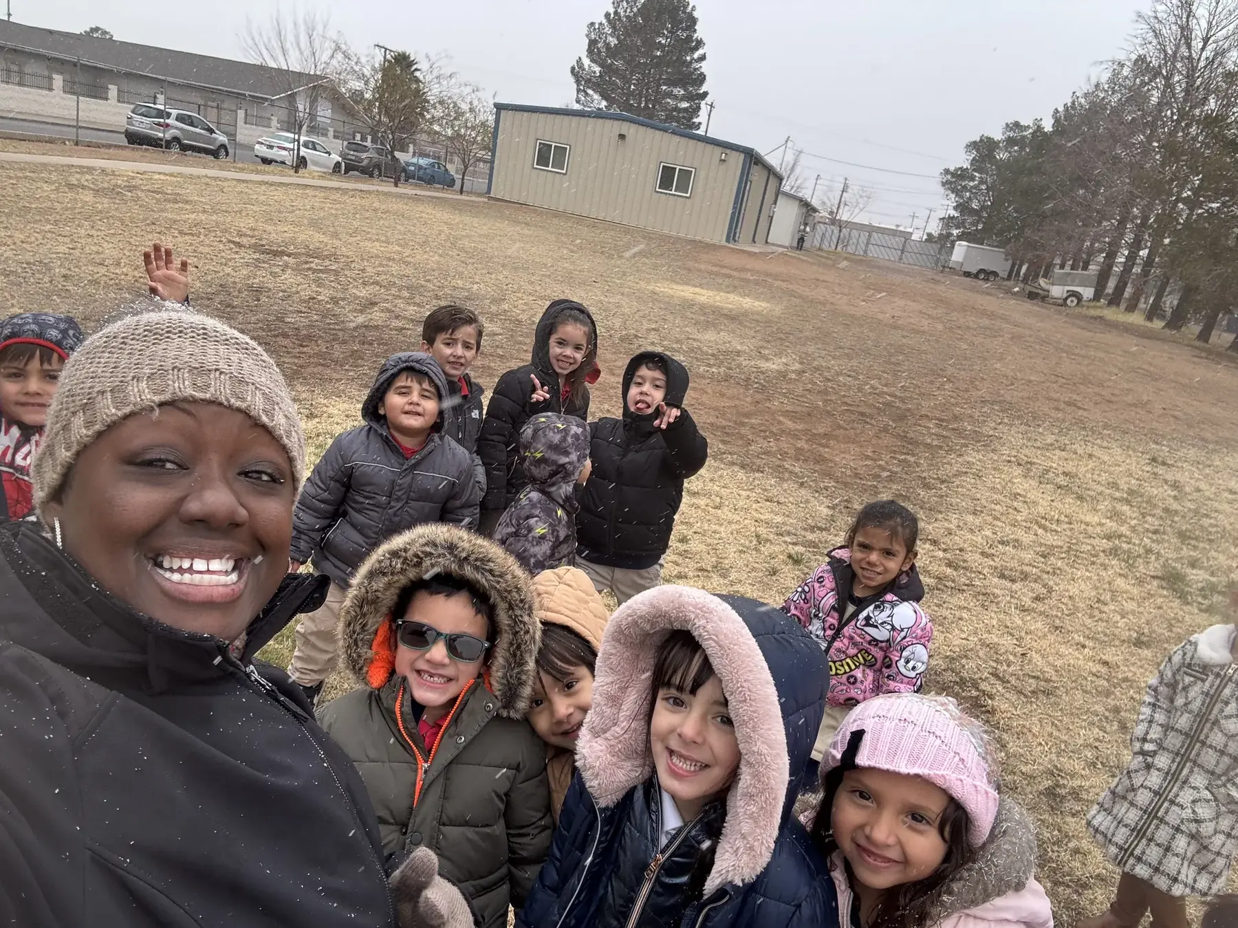 A NECA teacher outdoors with a group of elementary students in winter coats.